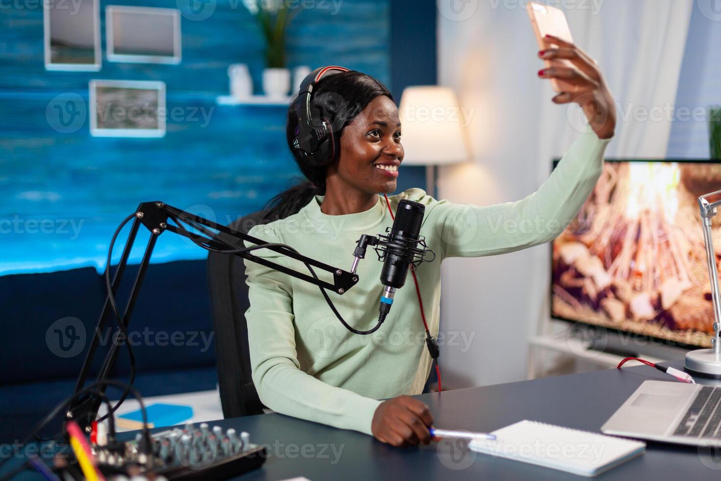 African influencer recording podcast and taking selfie in home studio. On-air online production internet podcast show host streaming live content, recording digital social media. photo