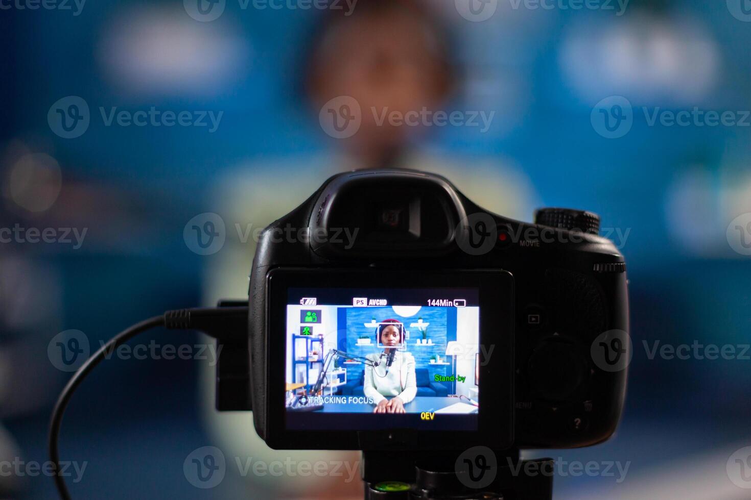 Close up professional camera sitting in front of dslr recording online show. Speaking during livestreaming, blogger discussing in podcast wearing headphones. photo