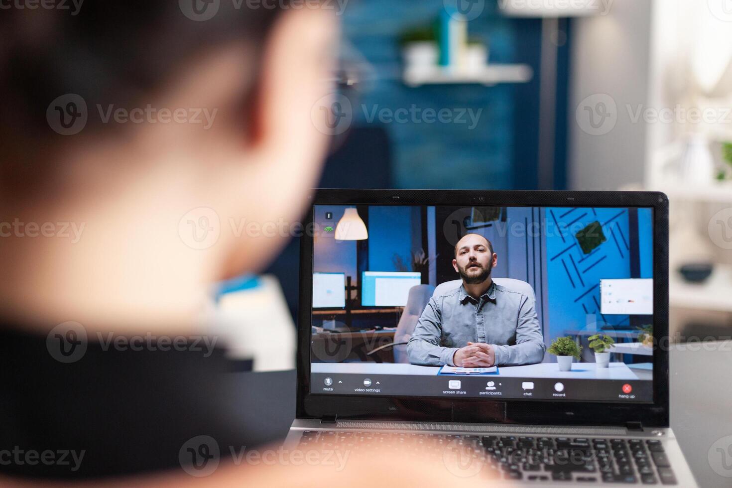 Student discussing with her teacher on online videocall about e-learning platform using laptop computer. Young woman having remote education during coronavirus quarantine while sitting in living room photo