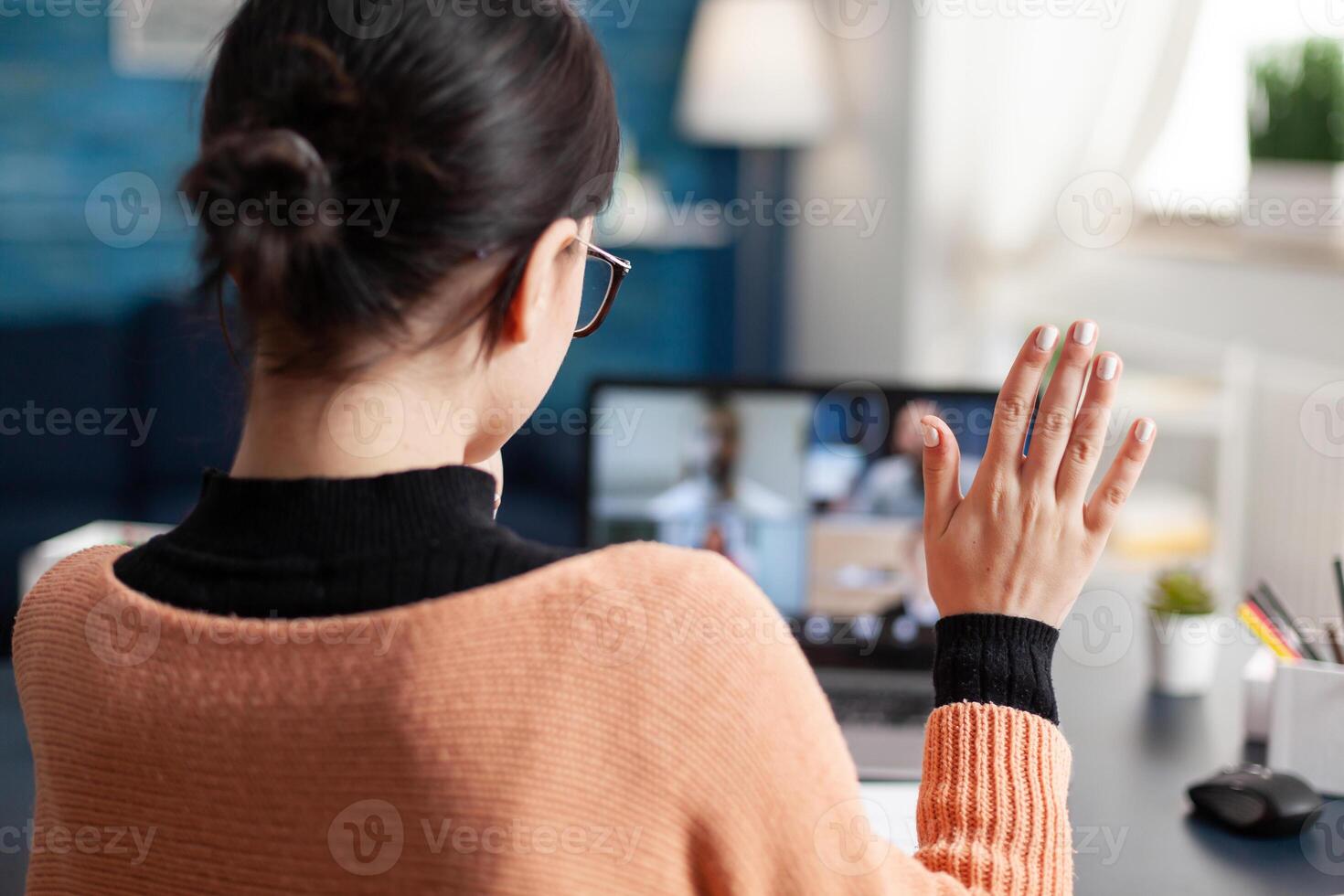 Student chatting with university collegue during online webinar using laptop computer, Young woman having remote education during coronavirus quarantine while sitting in living room photo