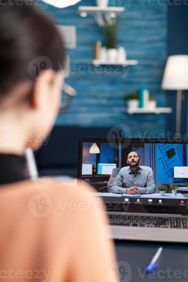 Caucasian female chatting with her math teacher during university videocall conference using laptop cumputer. Student working at communication lesson while sitting at desk in living room photo