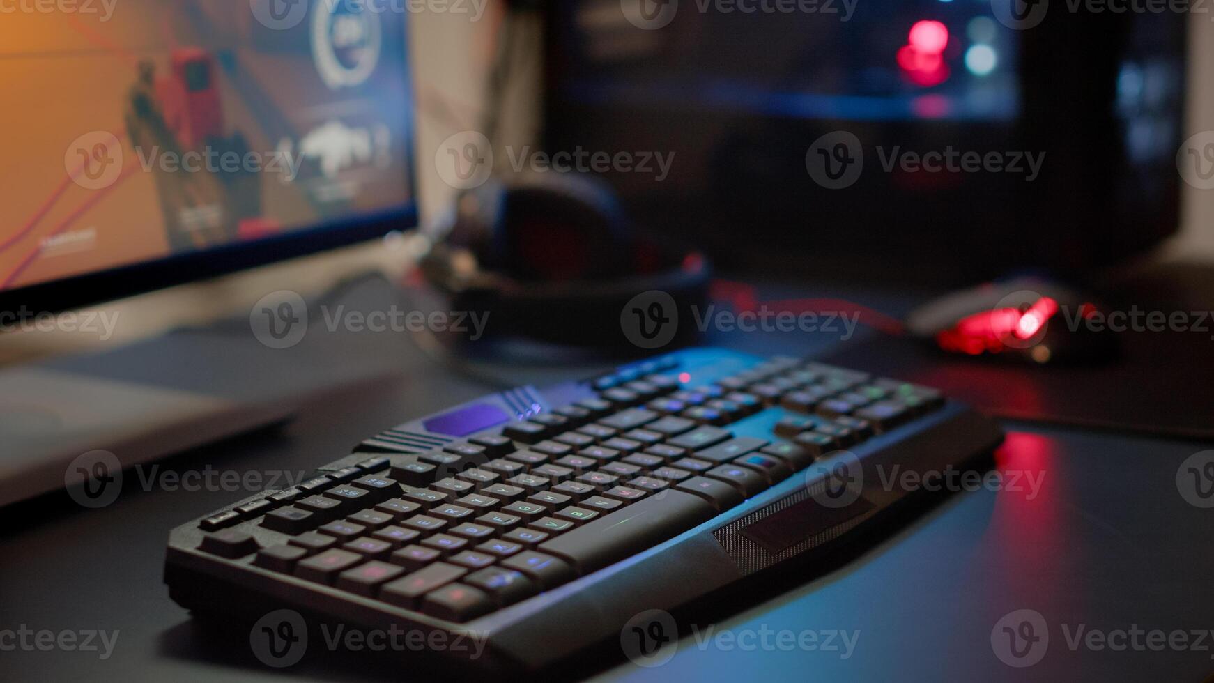 Close up of professional RGB keypad in empty gaming room prepared for streaming online tournament, display with first person shooter playing on it. Game studio with powerful computer photo