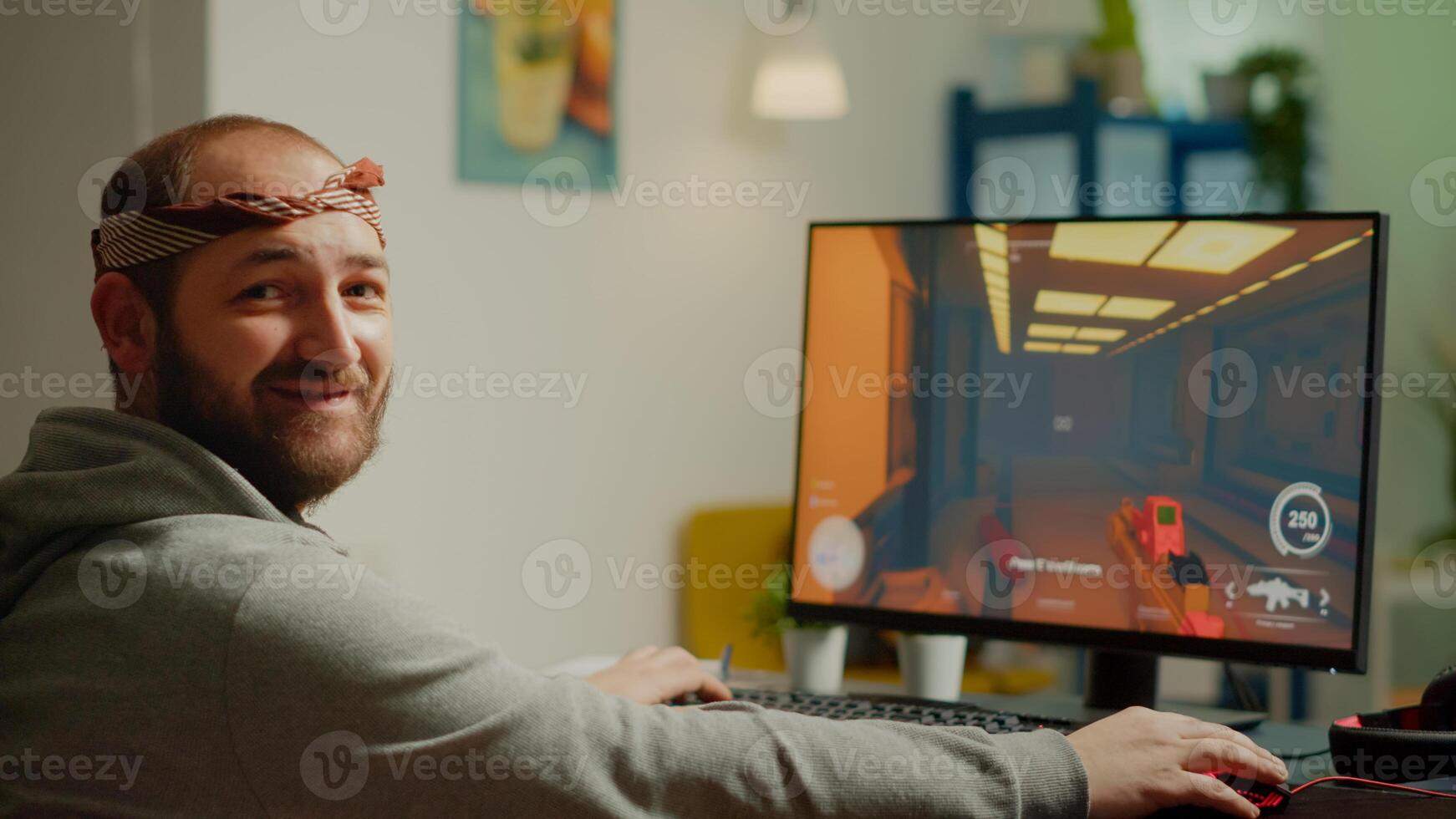 Pro man gamer turning head looking at camera smiling playing FPS shooter videogame during gaming championship in cyberspace. Esports player performing on powerful computer in online tournament photo