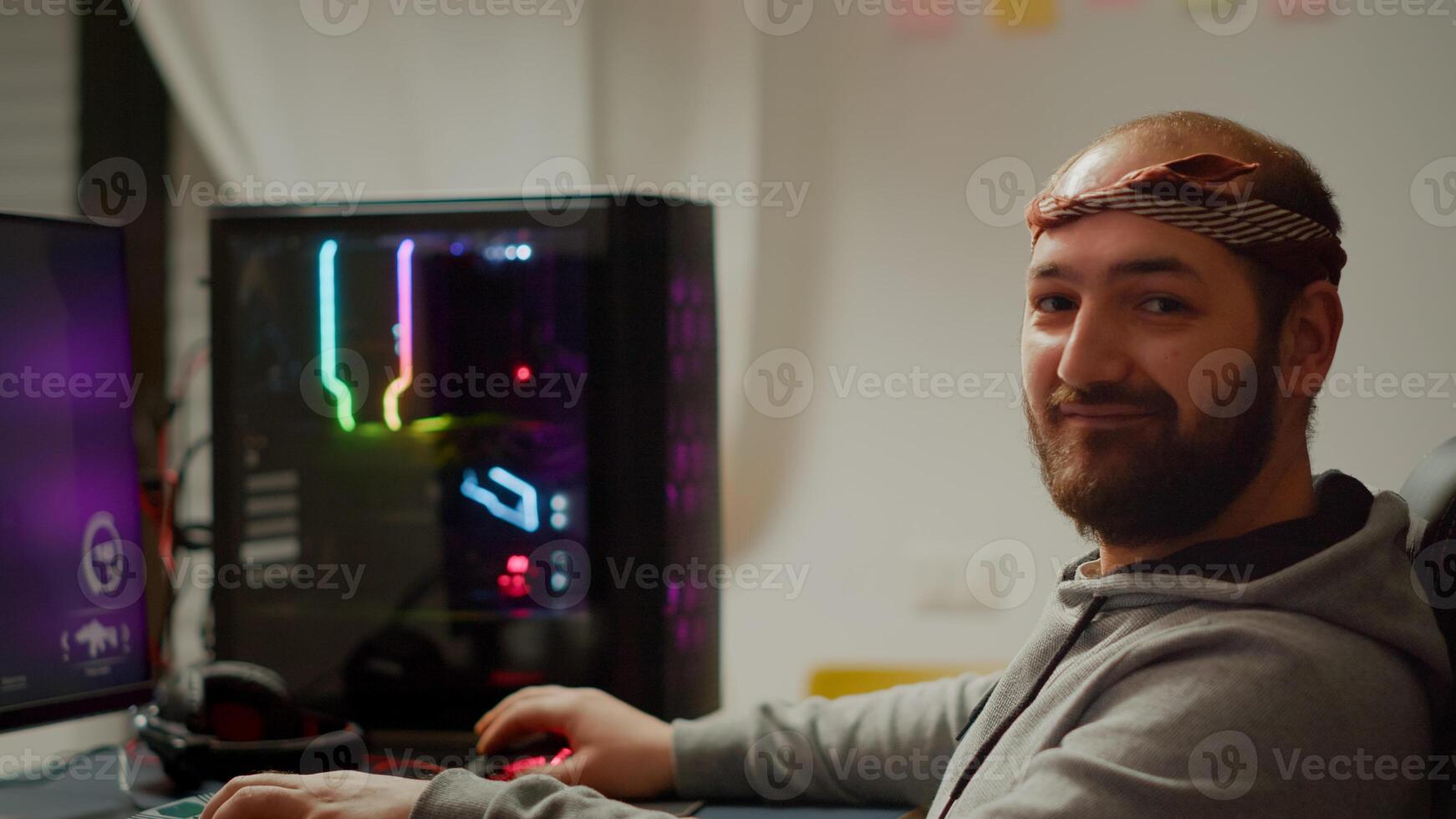 Portrait of young pro gamer man sitting at powerful personal computer looking into camera. Concentrated cyber playing first-person space shooter online game performing during gaming tournament photo