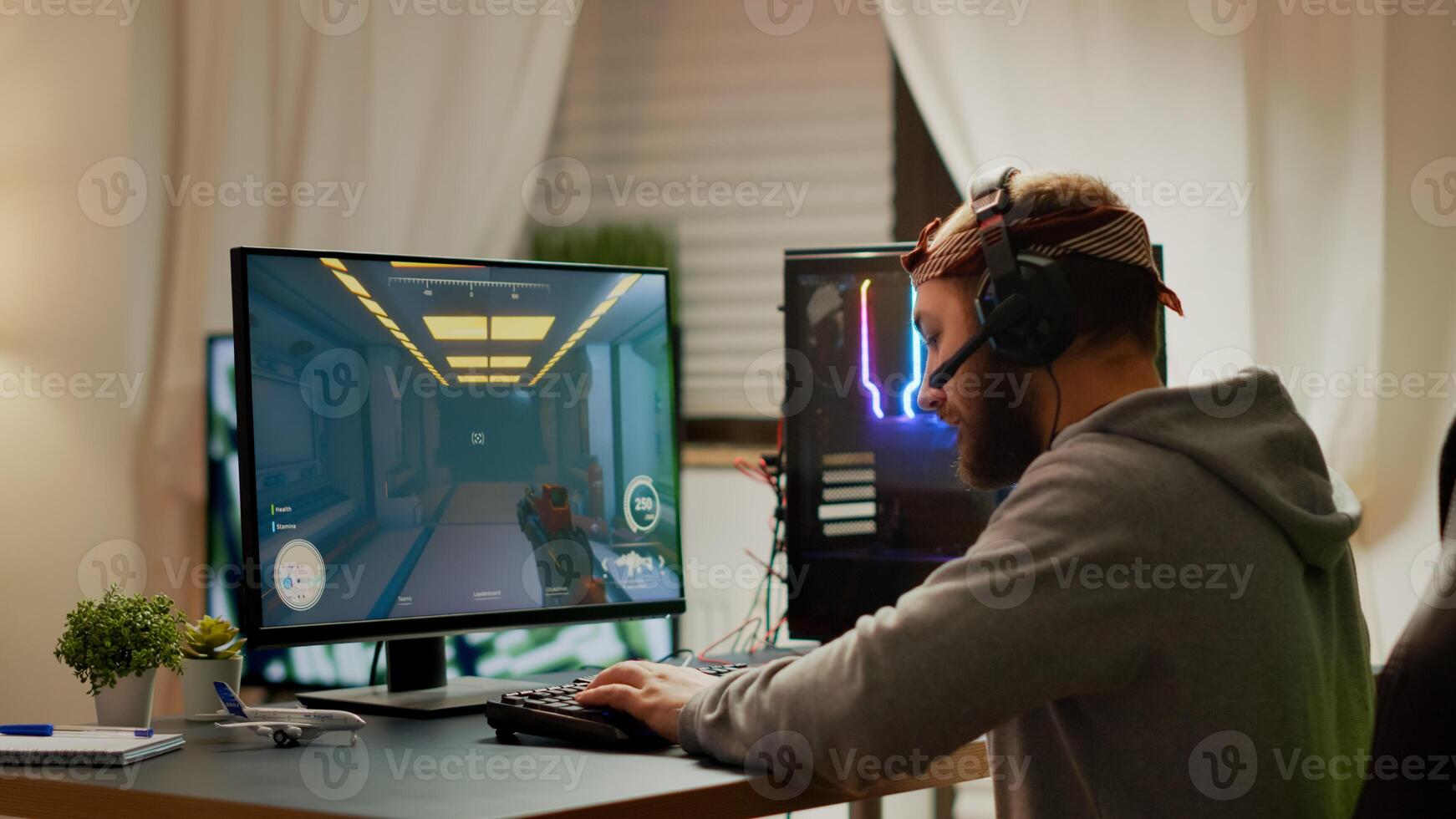 Cyber sport gamer wearing headphones playing first person shooter videogame participating in eSports tournament perforing at RGB prowerful personal computer. Pro cyber streaming gaming championship photo