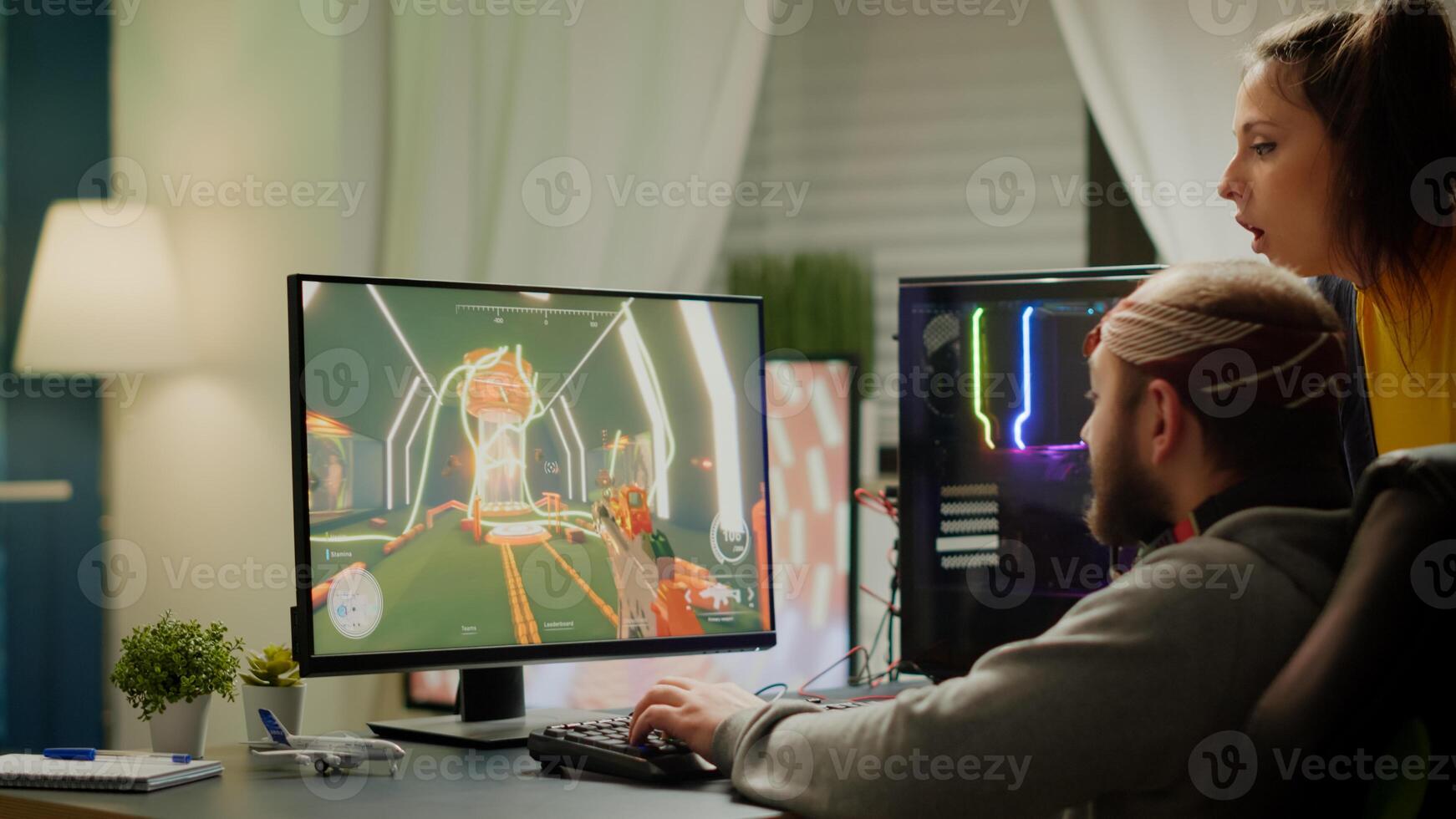 Couple of gamers playing first person shooter videogame on RGB powerful computer screaming, supporting each other during online competition. Pro cyber man performing from home at virtual tournament photo
