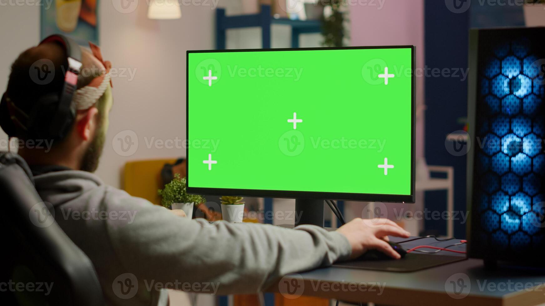 Gamer playing games on powerful computer with green screen chroma key desktop mock-up display in gaming home studio. Player using RGB keyboard with isolated monitor streaming game wearing headset photo