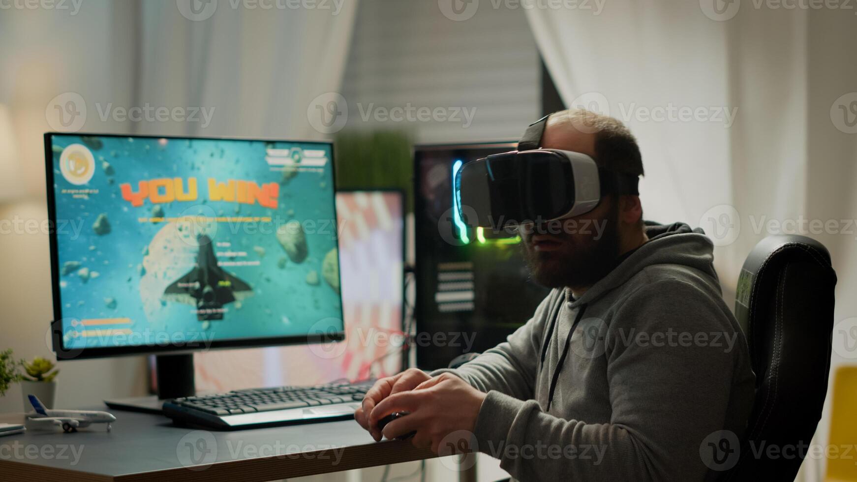 Videogame player with VR headset raising hands after winning space shooter competition. Professional pro gamer playing online games with new graphics on powerful computer from gaming room photo