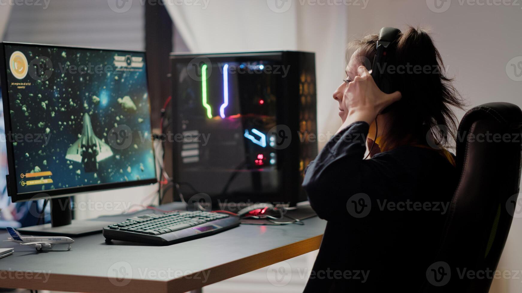 Professional esport woman gamer coming in gaming room playing space shooter game during online championship event. Streaming cyber performing on powerful computer during virtual tournament photo
