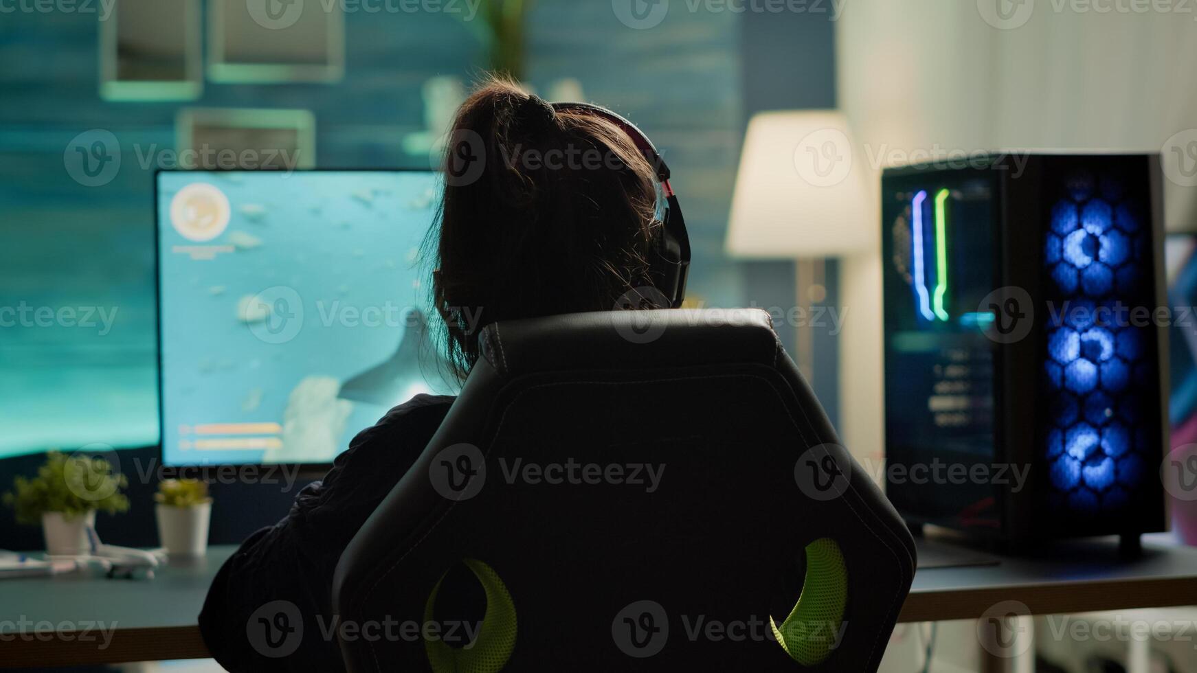 Back view of digital pro player playing online space shooter game competition using RGB prowerful personal computer. Professional cyber woman gamer with headset streaming gaming championship photo