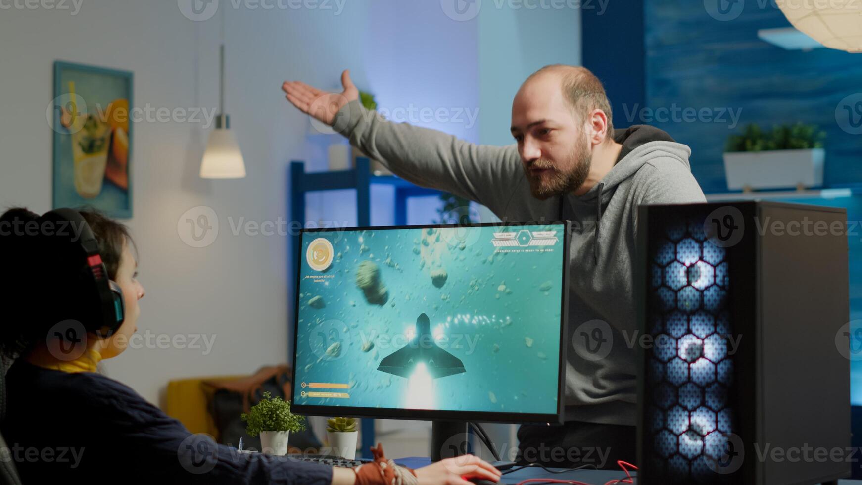 Nervous man screaming at woman while she is playing space shooter game on RGB powerful computer and streaming online competition. Pro cyber with headset performing during virtual tournament photo