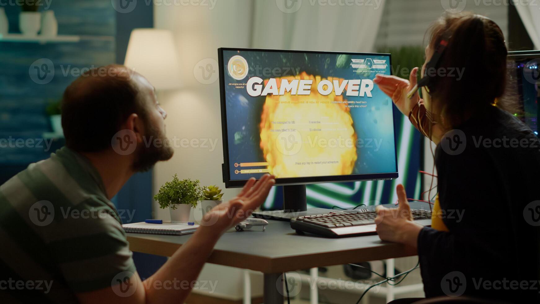 Gaming over for nervous pro couple gamers, playing space shooter during virtual competition tournament using professional headset. Sad online streaming cybers performing using RGB powerful computer. photo