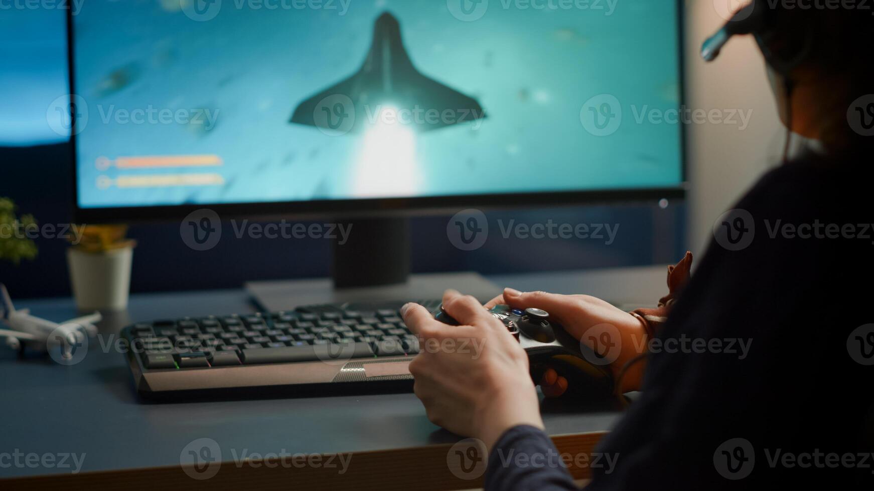 Closeup of competitive woman player holding joystick playing space shooter games at powerful computer late night. Professional gamer using wireless controller for online gaming championship photo