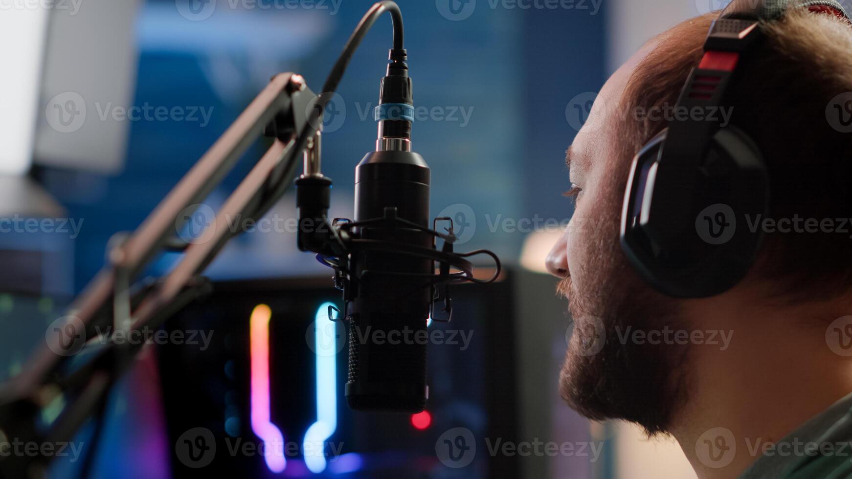 Portrait of cyber talking on stream chat with players using micorphone and powerful computer. Streamer man sitting on gaming chair playing space shooter game during online esports tournament. photo