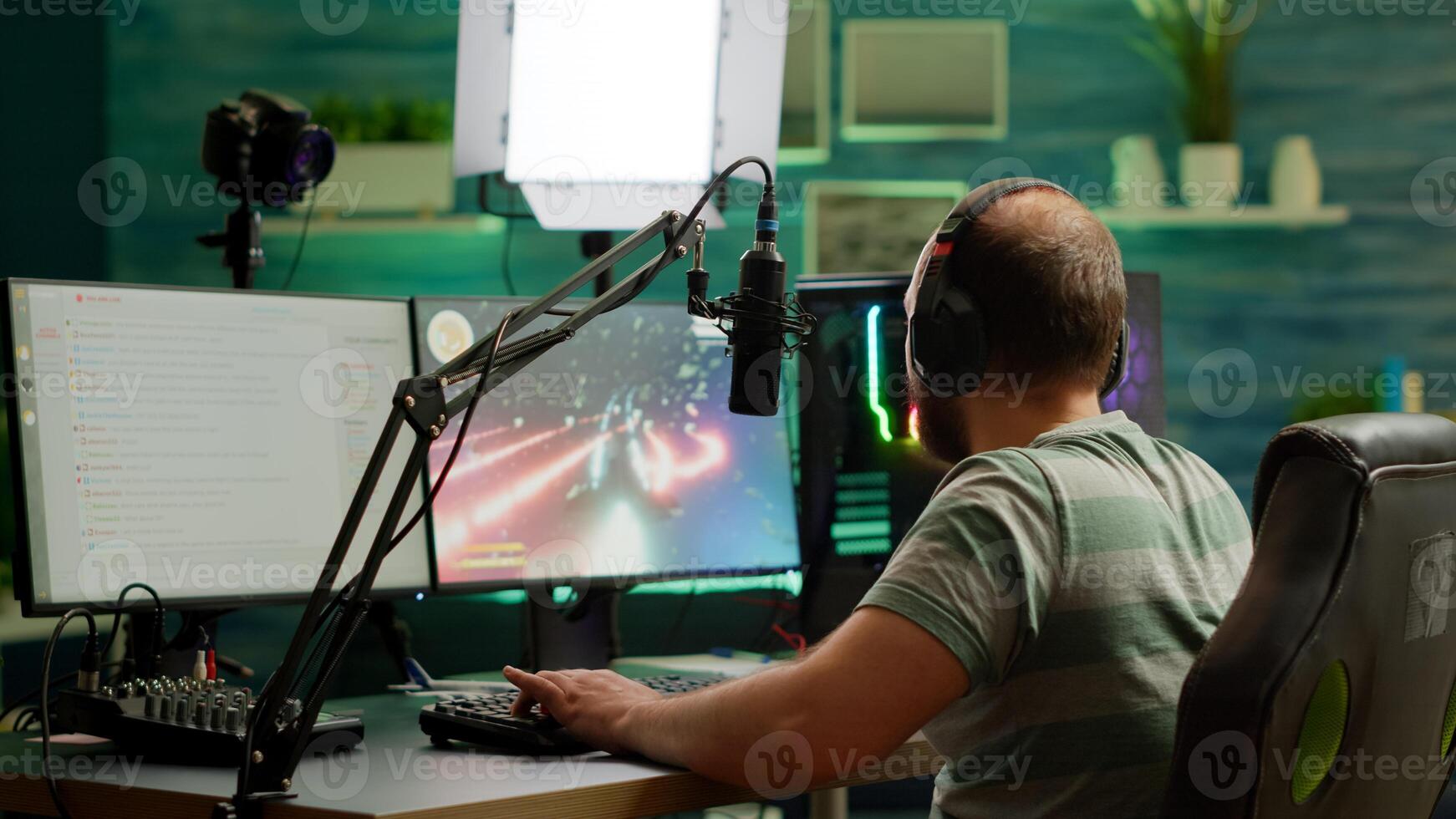 Man streamer playing space shooter videogame using headset, talking on stream chat and microphone. Online streaming cyber performing on RGB powerful professional computer during gaming tournament photo