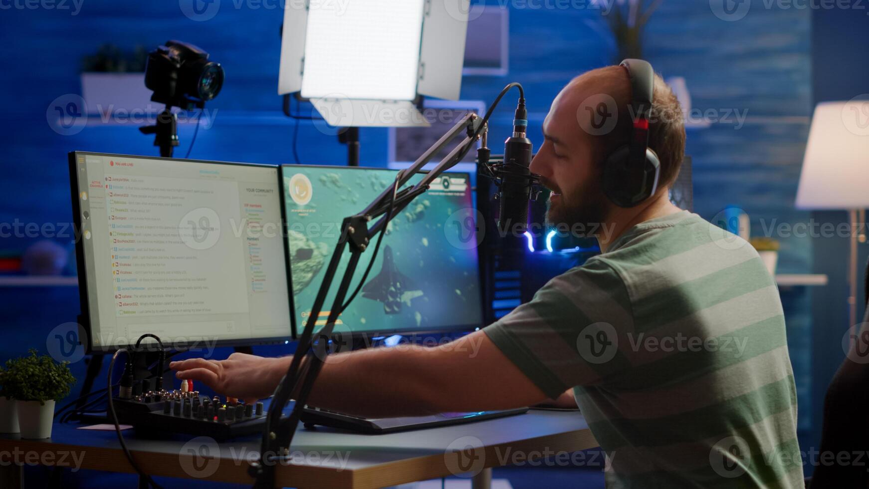 Man streamer cyber checking sound at mixer performing space shooter game on RGB powerful computer talking with players on stream chat and microphone in gaming competition. Player man streaming photo