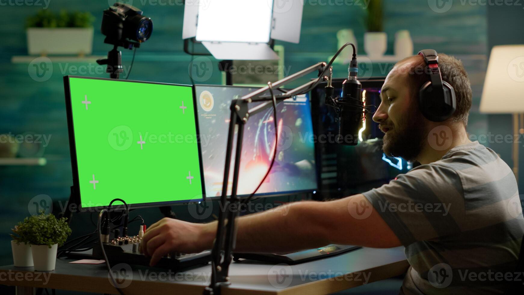 Professional cyber streamer playing online videogames on professional powerful computer with green screen mock up, chroma key display. Gamer playing space shooter game with isolated desktop streaming photo