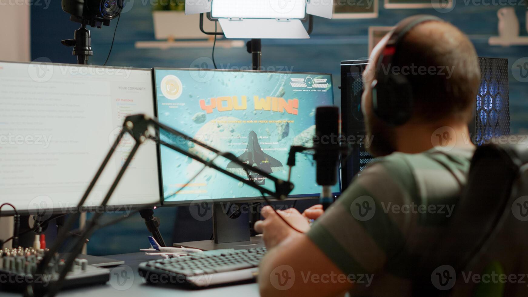 Entusiastic man gamer streamer wining space shooter games holding joystick playing on professional RGB keyboard and talking on stream chat. Pro cyber using microphone in gaming tournament photo