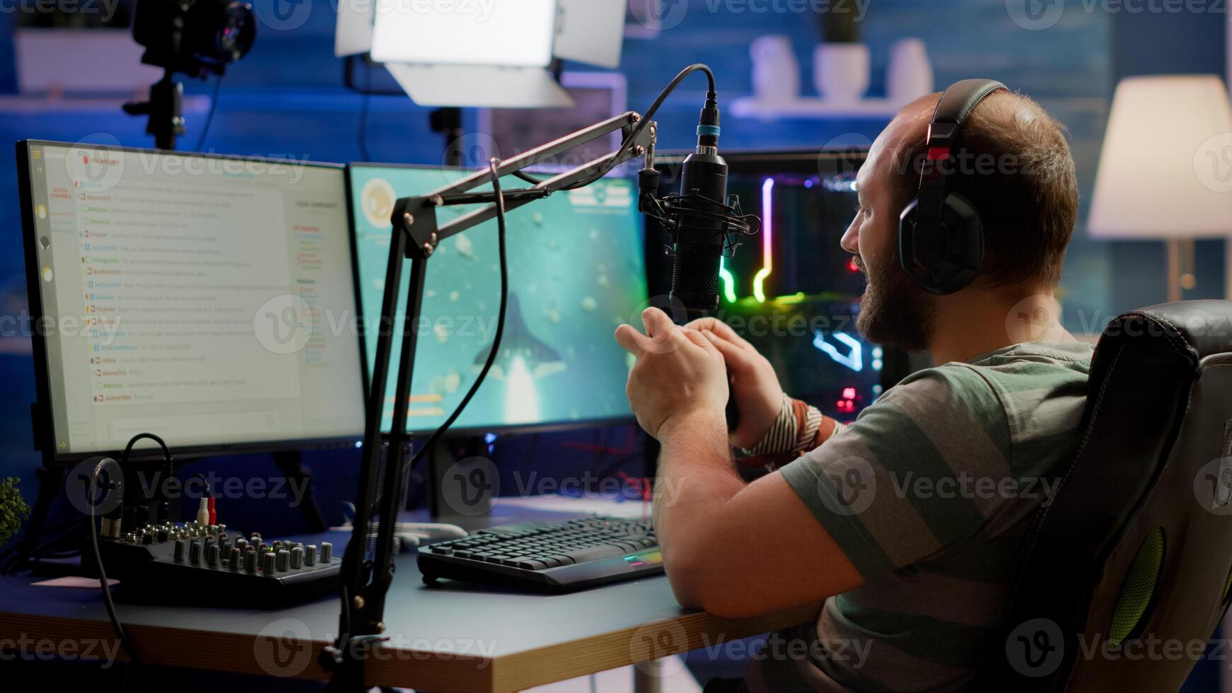 Concentrated gamer playing shooter game in gaming competition using wireless controller wearing professional headphones. Online streaming cyber performing during tournament using RGB powerful PC photo