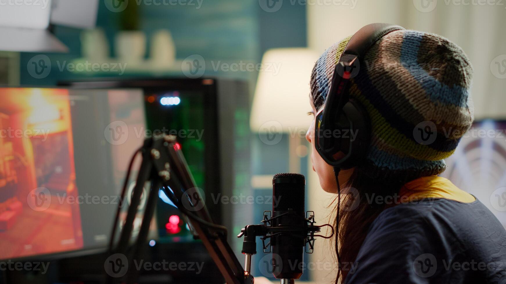 Close-up of streamer playing first person shooter game using RGB powerful computer during esport tournament. Player performing online gaming competition late night in streaming home studio photo