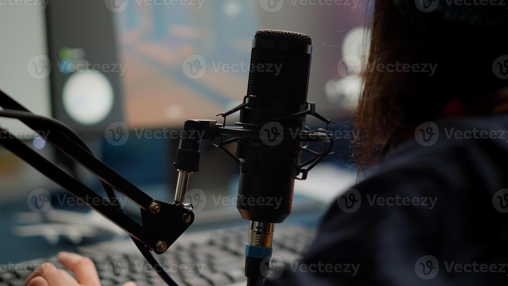 Close-up of pro streamer woman talking at microphone during virual games tournament. Cyber gamer streaming playing online games using RGB keyboard mouse late at night in gaming studio photo