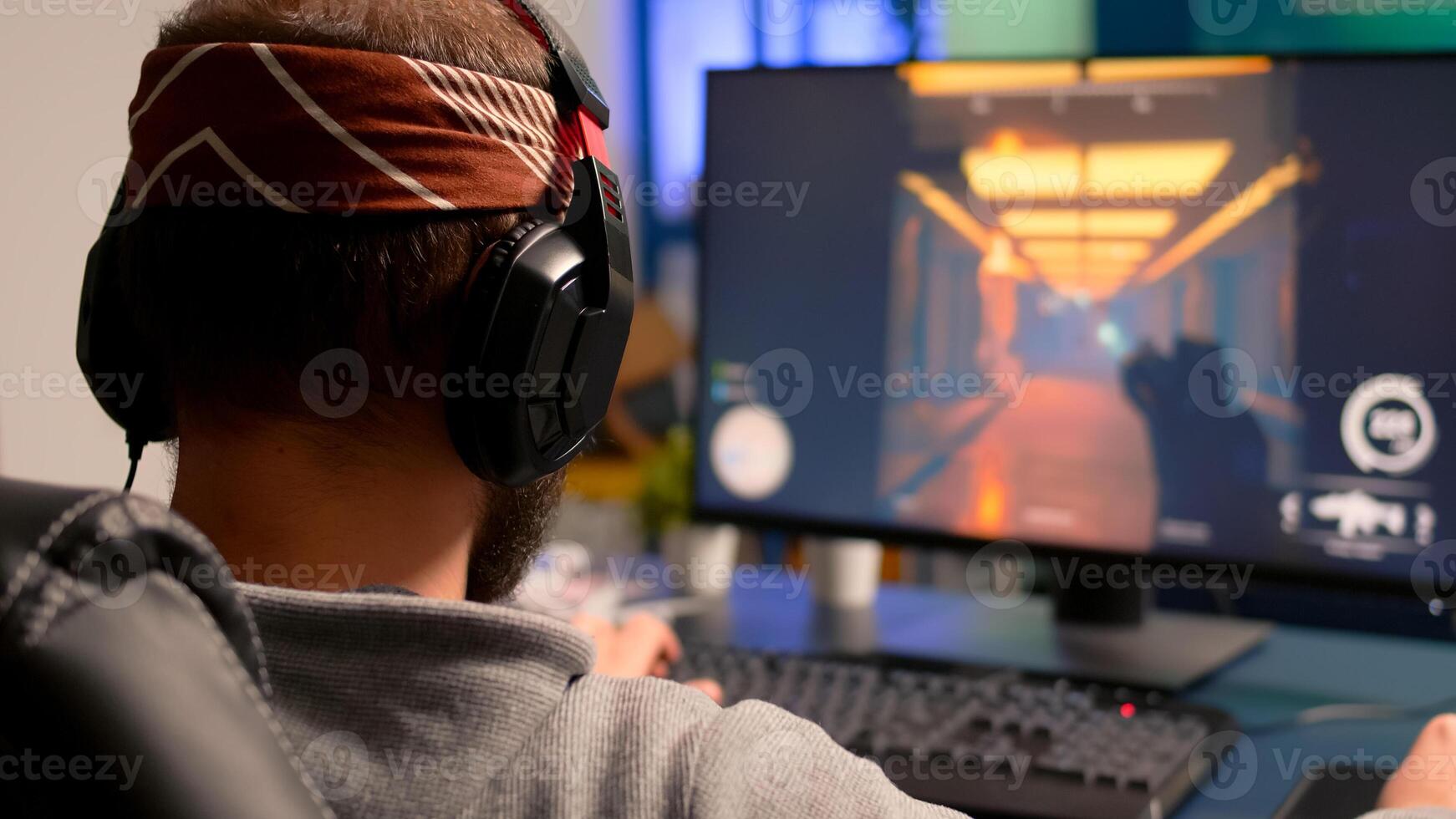 Pro gamer playing on powerful computer first person shooter game during live championship, wearing headphones. Competitive player streaming game tournament using professional equipment photo