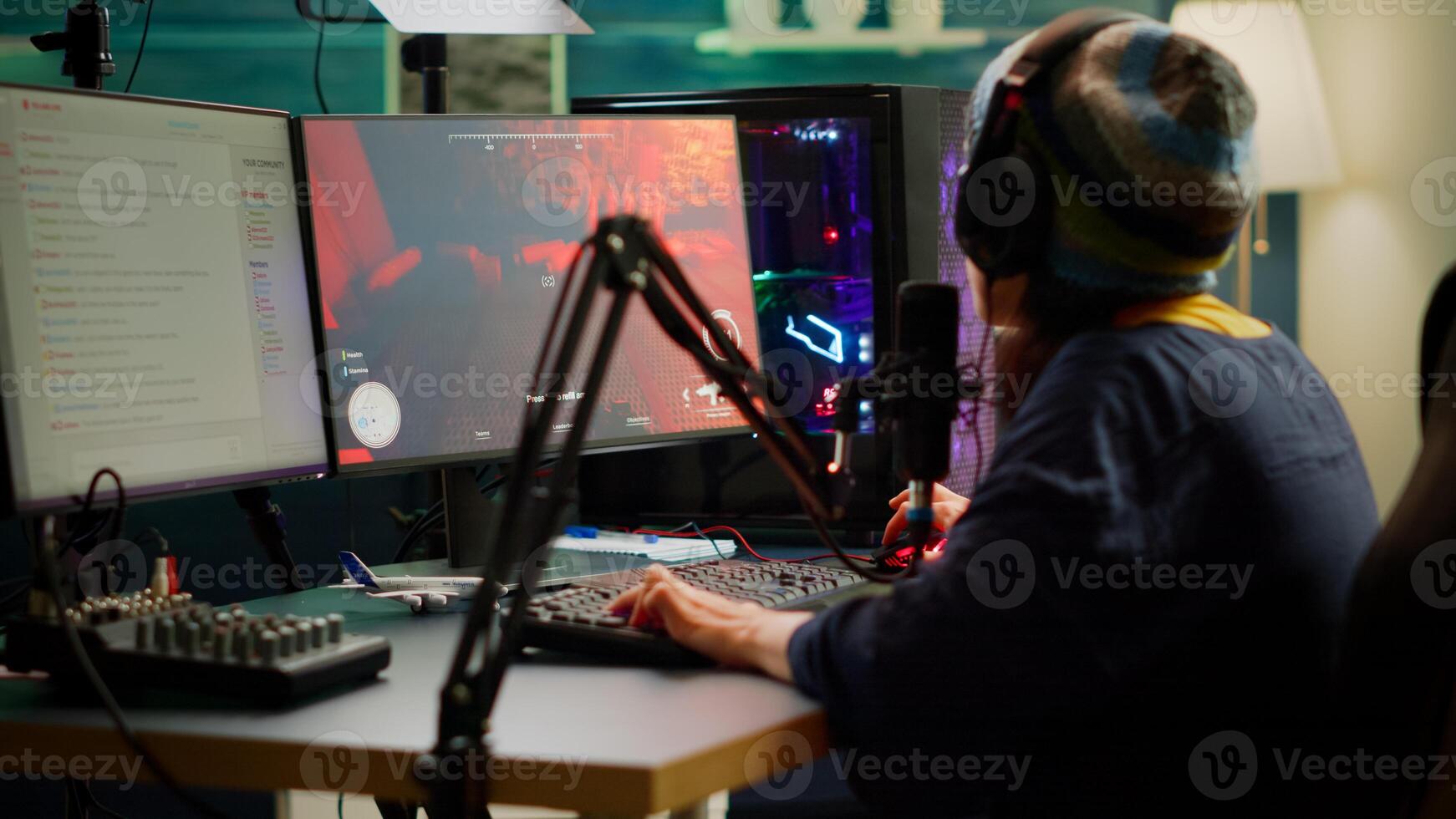 Streamer playing FPS videogames and talking with team mates on streaming open chat using professional microphone. Cyber performing in online tournament on RGB powerful computer in gaming sudio room photo