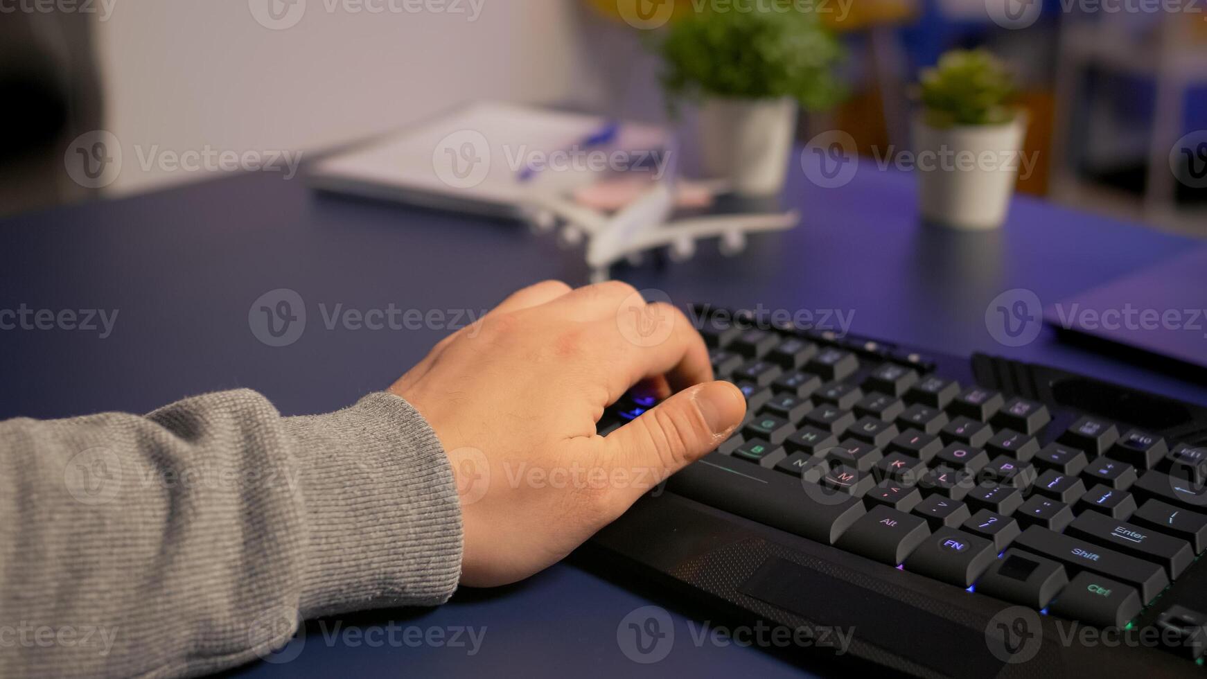 Closeup of gamer typing on professional RGB keyboard, playing online game in gaming home studio. Player using modern equipment streaming e-sport competition late at night photo