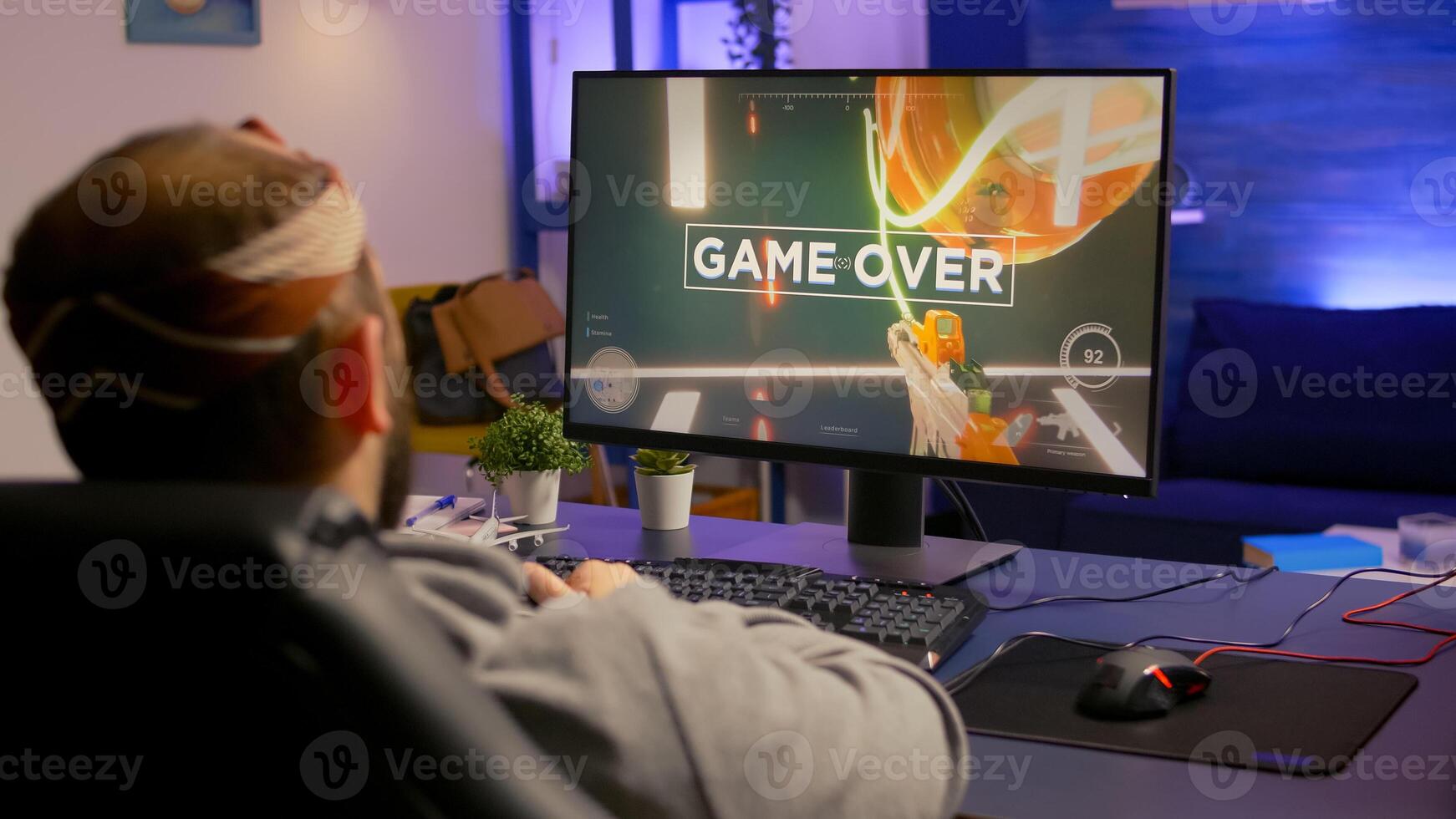 Game over for upset gamer playing on powerful computer first person shooter game during online tournament. Defeated man with headphones streaming online cyber performing late at night in gaming room photo