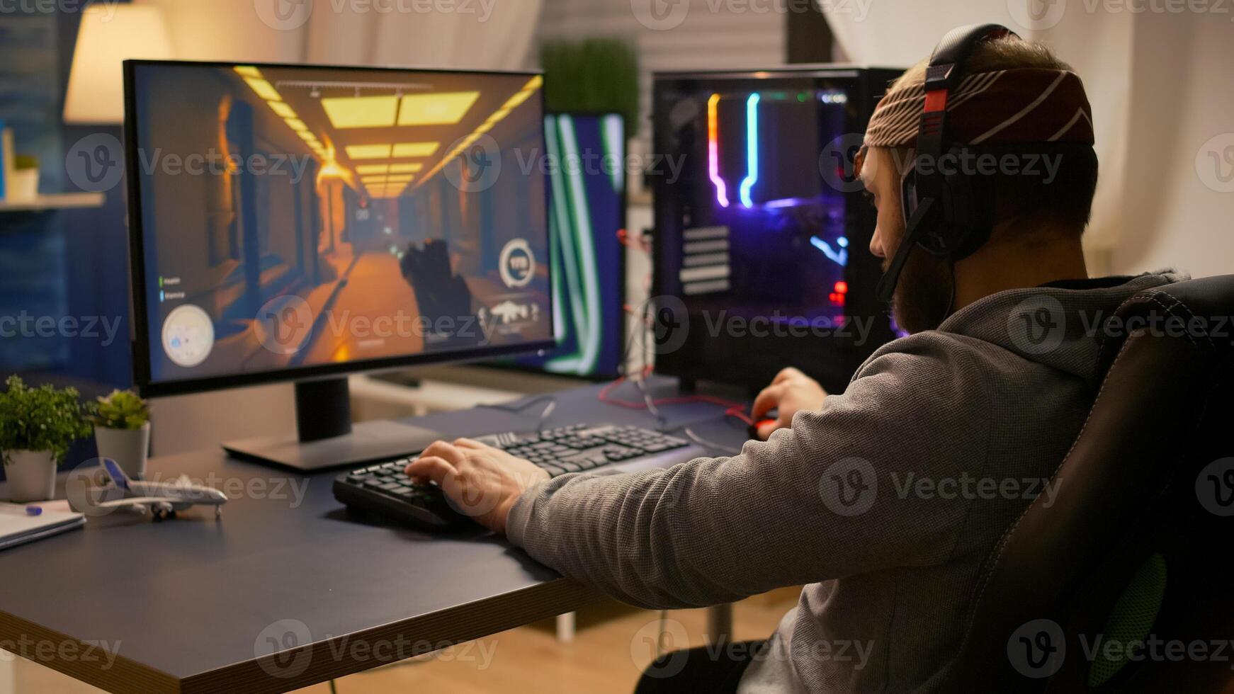 Videogamer winning first person shooter tournament using RGB keyboard and professional headphones. Pro player man talking with other players online for game competition on powerful computer photo