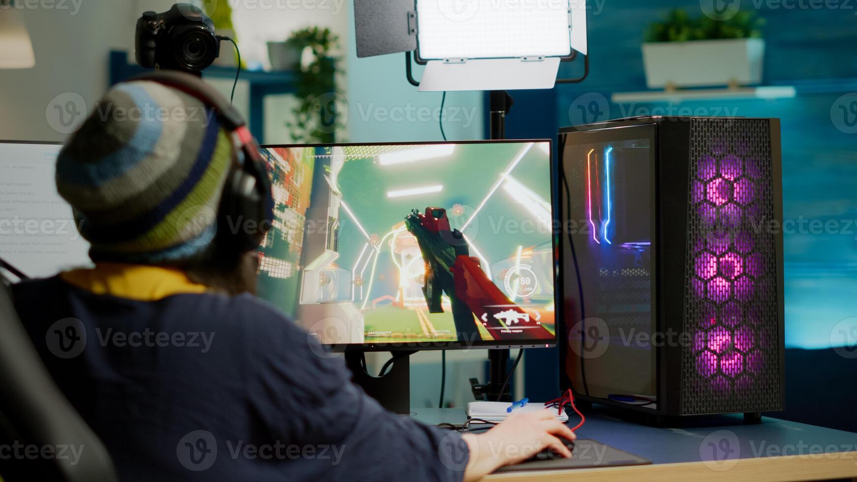 Back shot of pro streamer with headphone playing FPS videogame during esport competition using RGB powerful computer. Player sitting on gaming chair using streaming equipment late night in home studio photo