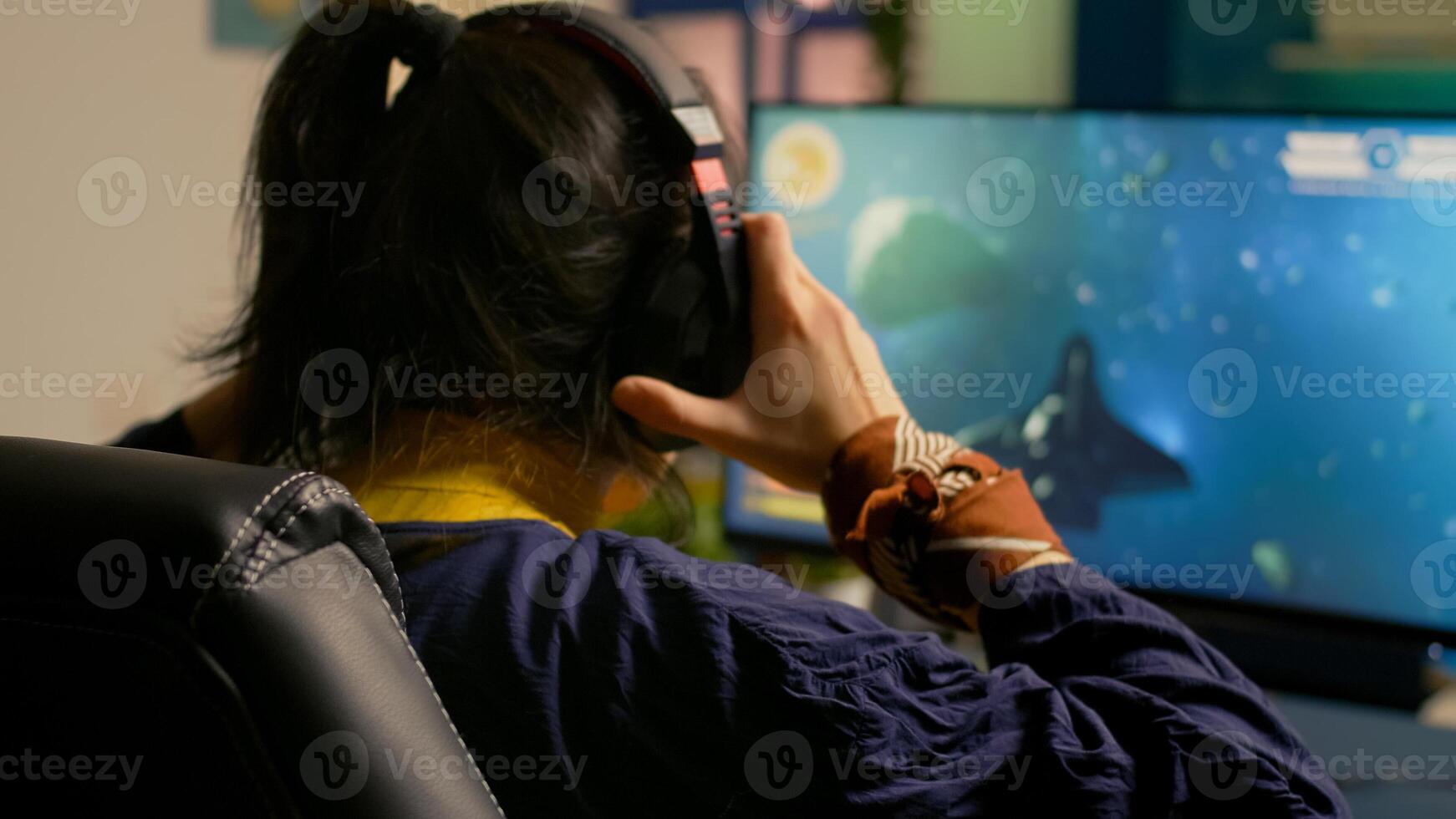 Cyber gamer playing space shooter game using RGB keyboard and professional headset during gaming tournament. Player talking with multiple players using headphones while streaming games photo