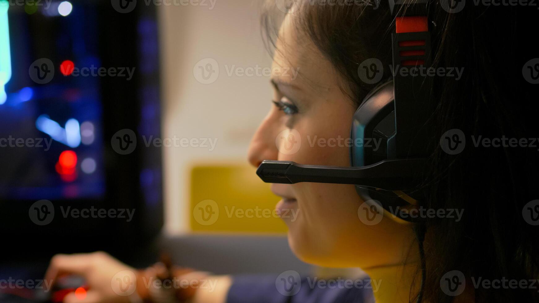 Close-up portrait of pro gamer playing online space shooter for digital competition. Player talking into microphone with multiple players using headset during gaming tournament photo