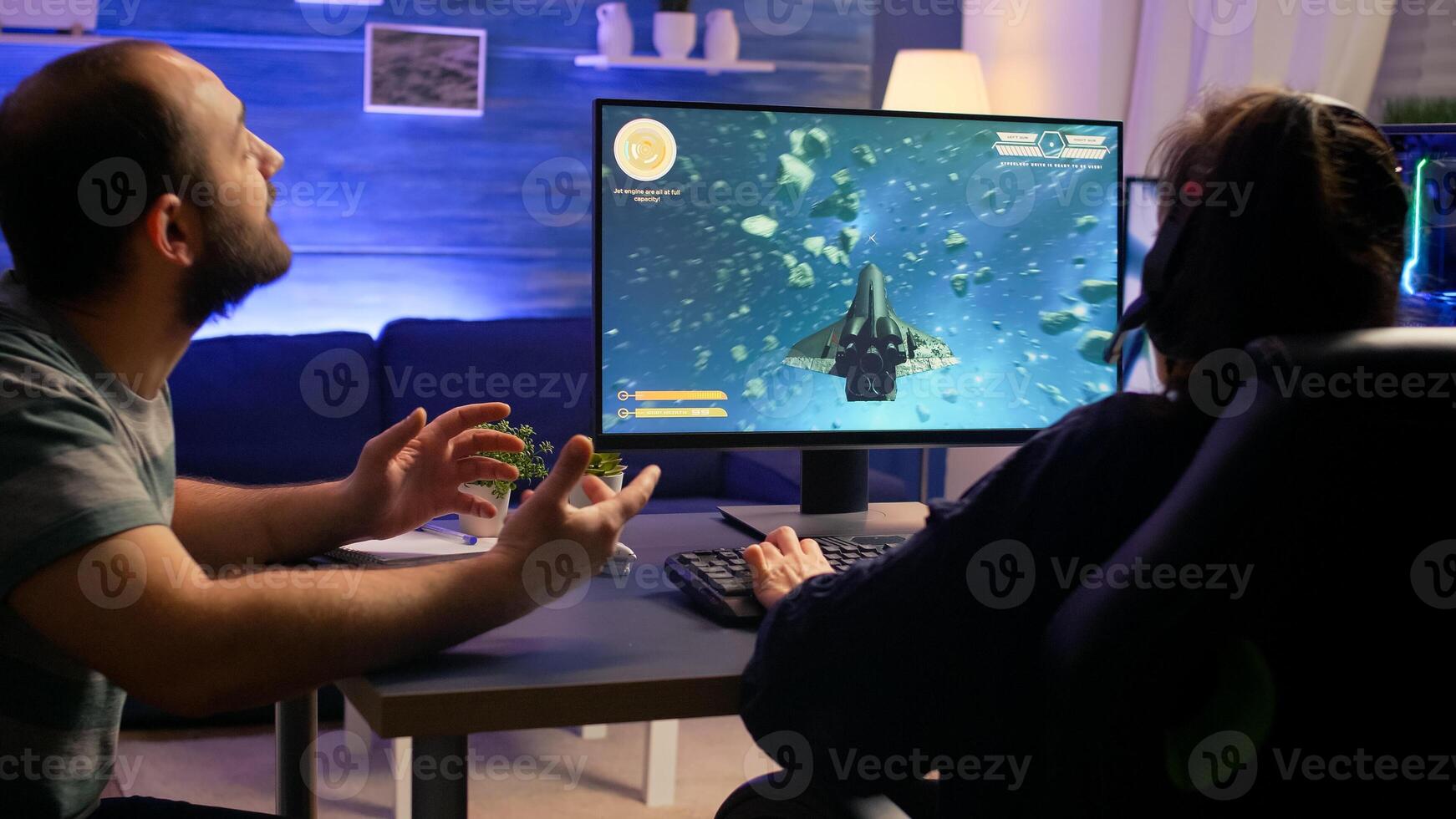 Couple of gamers making winner gesture while playing space shooter virtual championship. Defeated player with headphones streaming online cyber performing during online gaming competition. photo