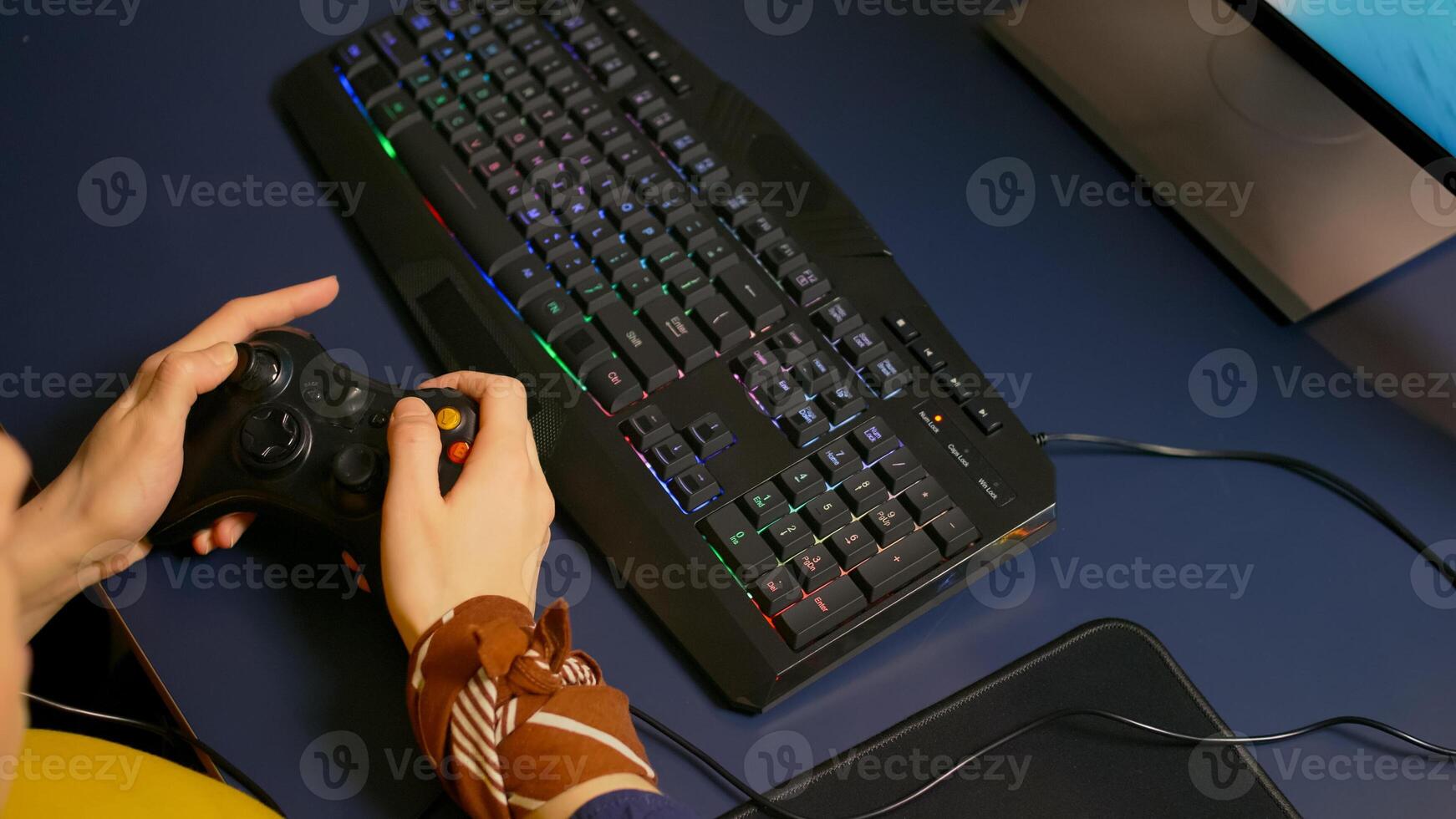 Closeup of wireless joystick and RGB keyboard, pro game r playing online games on powerful computer. Player using professional equipment during gaming online competition photo