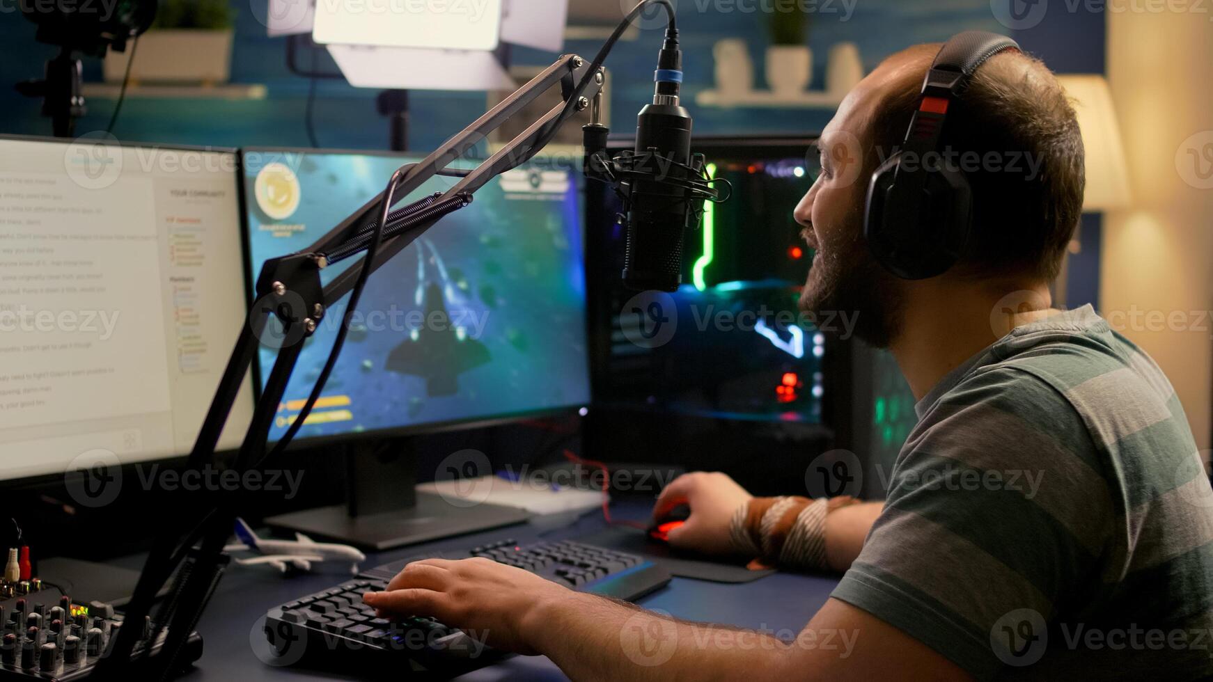 Streamer man wearing headset start to play online space shooter games. Pro e-sport player playing gaming tournament on RGB computer, using modern streaming technology photo
