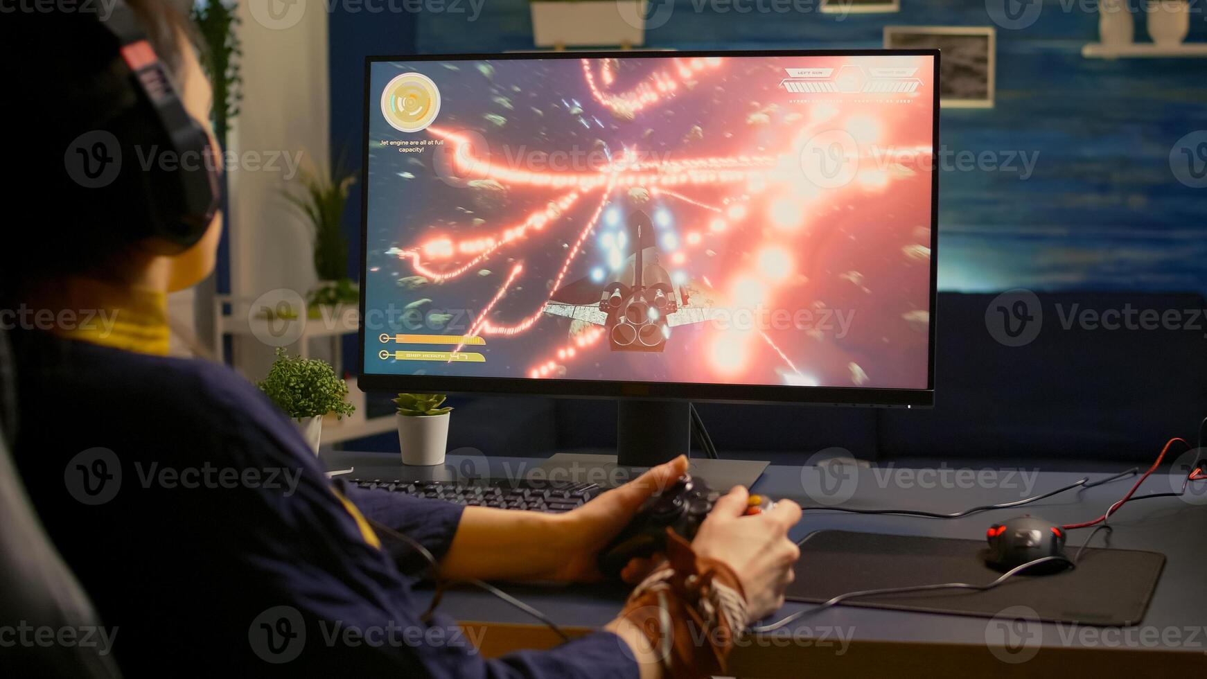 Over shoulder of focused cyber player wearing headset during online championship. Game over for pro gamer using controller for space shooter gaming competition late at night in living room photo
