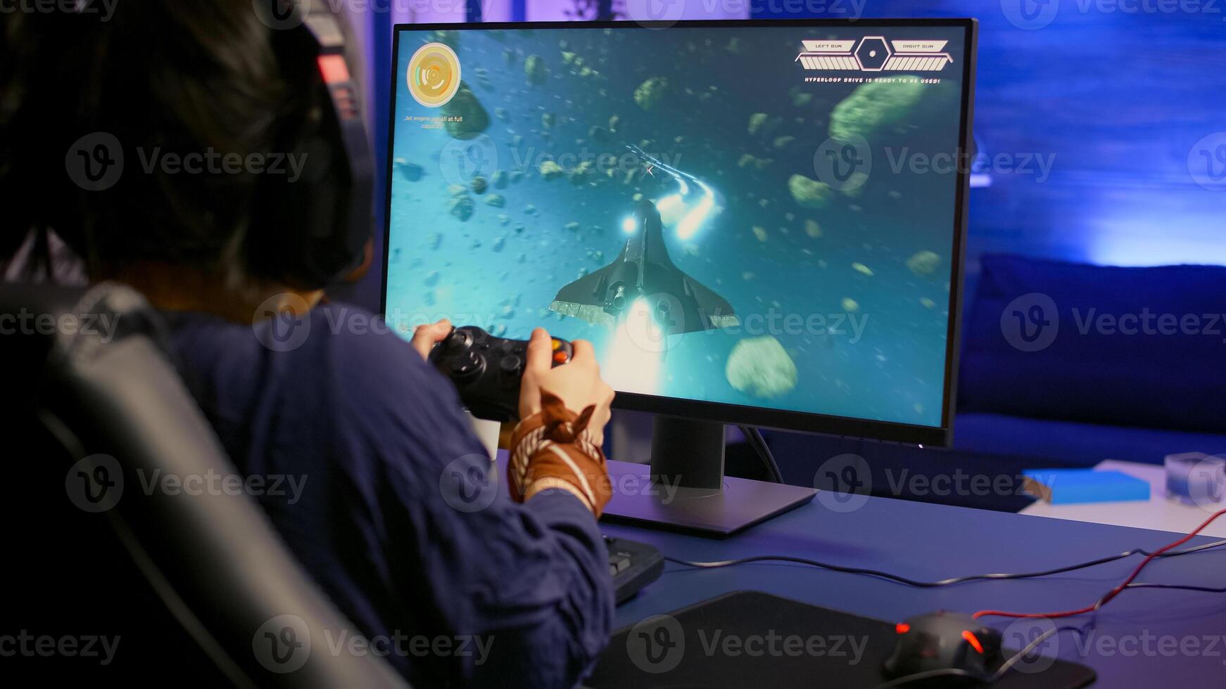 Back view of pro gamer winning space shooter game using headphones. Player using joystick for online championship sitting on gaming chair playing on professional powerful computer photo