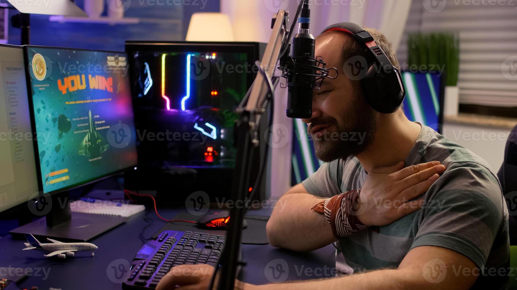Winner streamer playing online space shooter game in gaming room using RGB keyboard and system desktop. Cyber performing on powerful pc talking with players on chat open during live competition photo