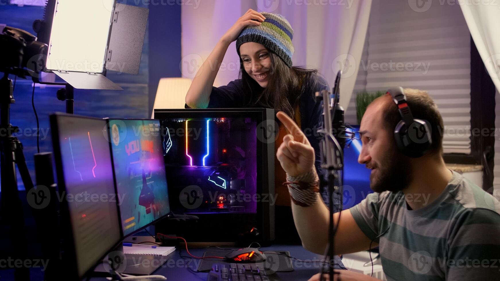 Side view of pro streamer couple performing online games using powerful computer with multiple monitors. Player playing space shooter games during e-sport online tournament in streaming studio photo