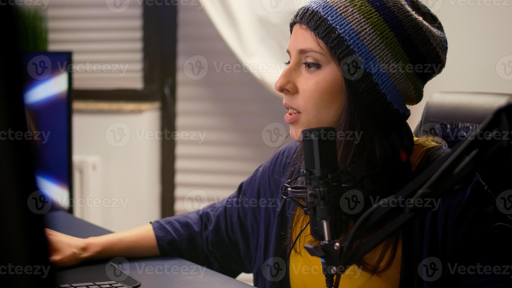 Close-up of pro streamer woman talking into microphone during virual games competition. Gamer streaming playing online games using RGB keyboard mouse late at night in home studio photo