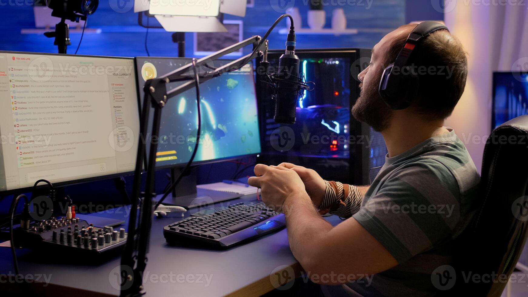 Back shot of pro streamer playing graphics cyber space shooter games using wireless joystick. Gamer performing on powerful pc talking with players on chat open during professional competition photo