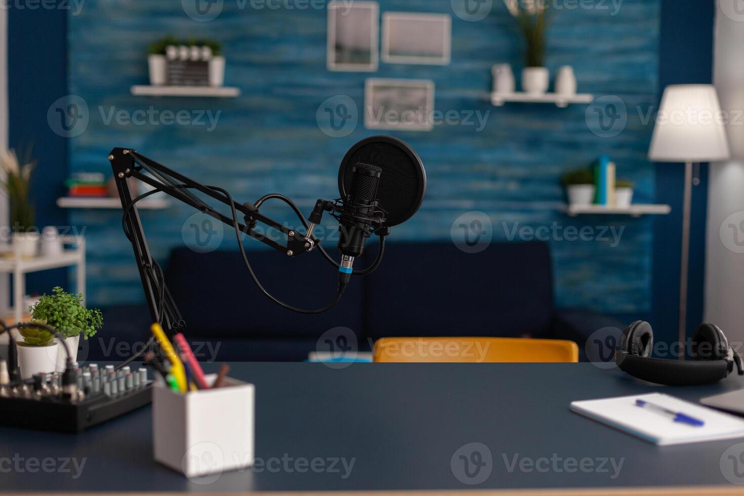 Empty home recording studio with podcast equipment. Professional microphone and headphones used for online broadcast on social media. Electronic audio livestream technology on desk. photo