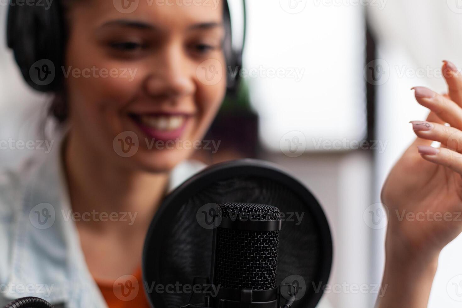 Closeup of woman influencer talking into microphone. Podcast presenter with headphones using recording equipment for live broadcast. Audio streaming for internet online radio production. photo