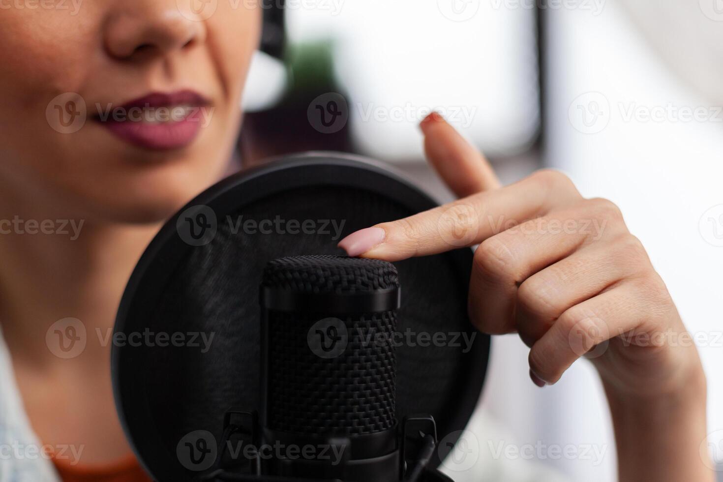 Closeup of content creator testing microphone sound. Woman influencer touching streaming equipment with finger. Vlogger doing sound check for online podcast streaming on social media. photo
