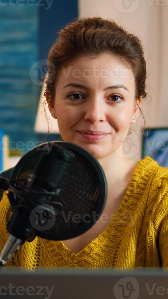 Woman blogger sitting in home studio looking at camera preapring for live recording podcast show. On-air online production internet broadcast host streaming web content record digital blog photo