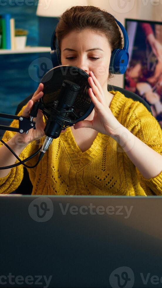 Creative influencer with headphones preparing to speak during live on social media recording vlog. On-air online production internet broadcast show host streaming podcast content from studio photo