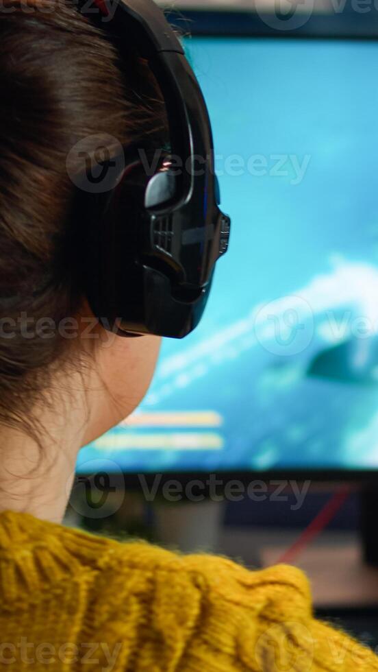 Back view of professional online gamer woman playing shooter game. Pro esport team player streamer playing gaming tournament on powerful RGB computer, using modern streaming technology photo