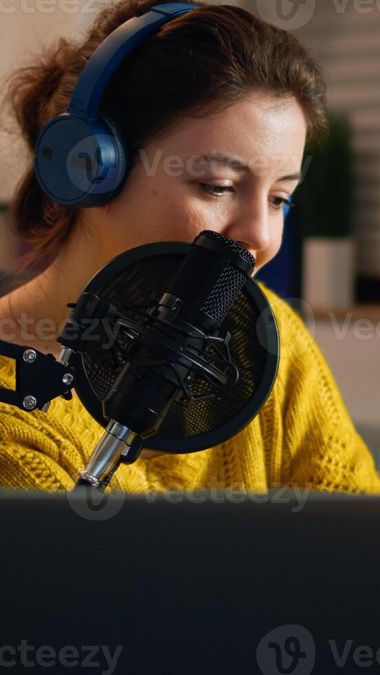 Happy blogger reading messages of fans using smartphone sitting in home podcast studio during livestreaming, recording. Online show On-air production internet broadcast host streaming live content photo