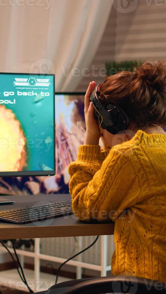 Upset professional woman gamer wearing headset losing shooter game round in cybersport competition. Tired player gaming online games on personal computer with modern technology network wireless photo
